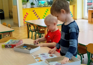 Dwóch chłopców bawi się przy stoliku wykorzystując puzzle i układanki edukacyjne.
